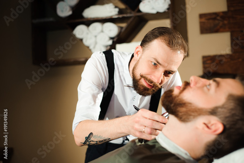 Master cuts hair and beard of men in the barbershop