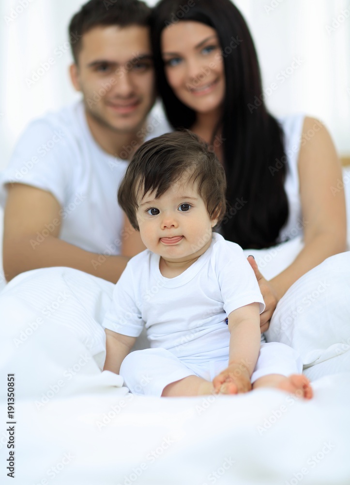 Happy couple and son sitting in bed