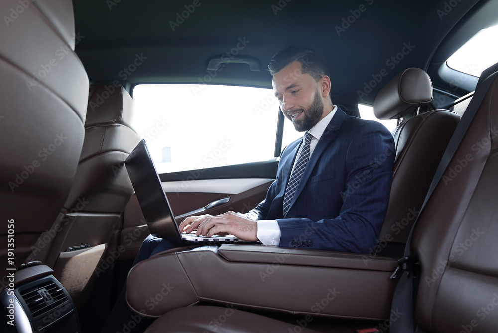 smiling businessman sitting in the back seat of a prestigious car smiling businessman sitting in the back seat of a prestigious car