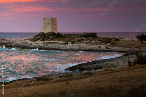 Dramatic sunset on Vieste coast, Italy, with old defense tower.
