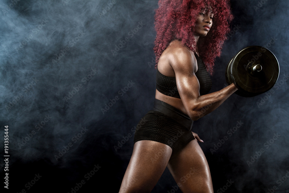Fototapeta Sporty beautiful woman with dumbbells makes fitness exercising at black background to stay fit