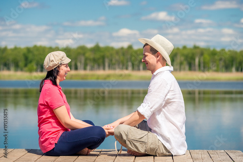 A young wife and husband on a wooden pier near the lake are resting © kosmos111