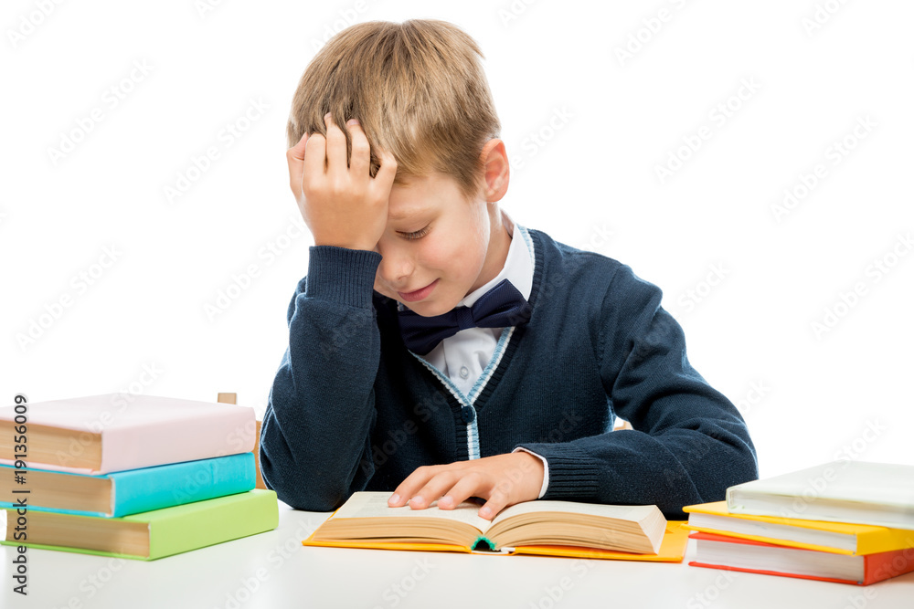schoolboy at the table reading a book, shooting on a white background schoolboy at the table reading a book, shooting on a white background