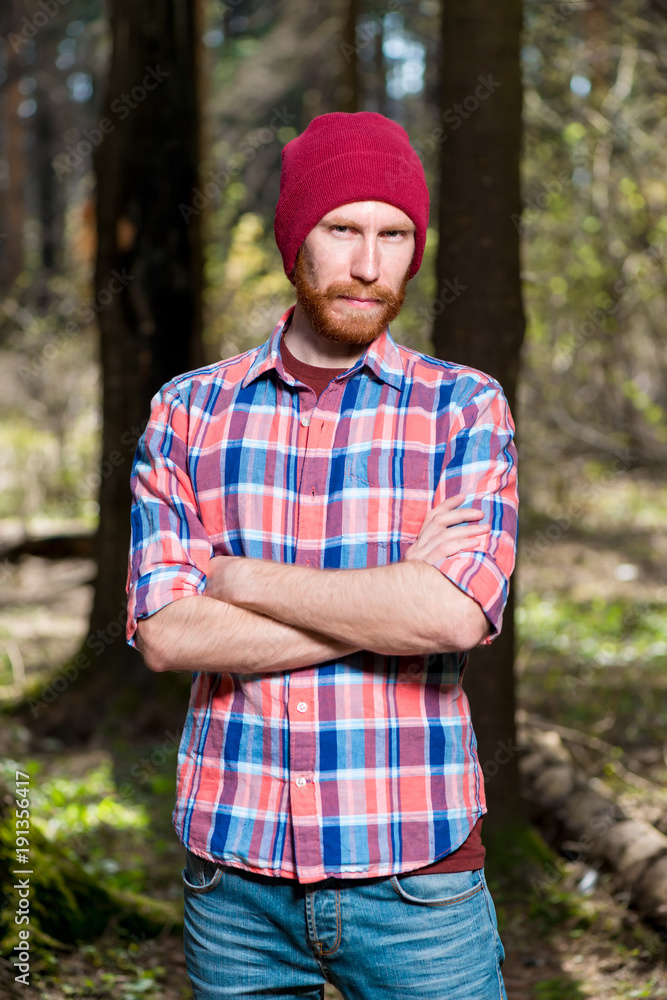 portrait of a man with a beard in a plaid shirt and hat in the woods portrait of a man with a beard in a plaid shirt and hat in the woods