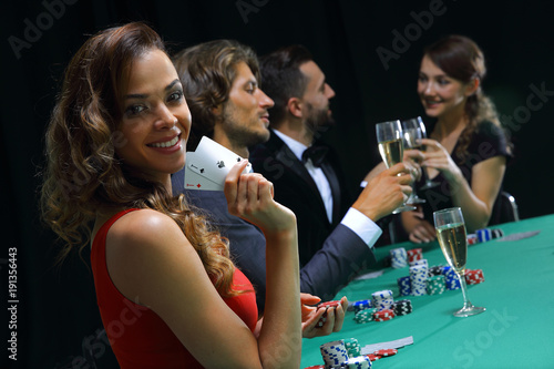 young brunette woman playing poker on black background