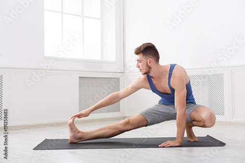 Man stretching at white background indoors