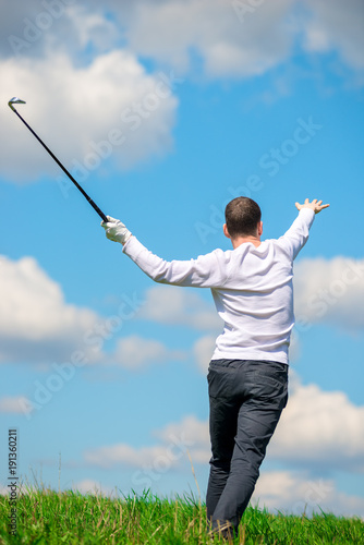 active golfer while playing golf on the golf club field, view from the back