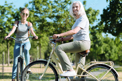 Active sport. Joyful positive aged woman riding a bike and smiling while leading healthy lifestyle