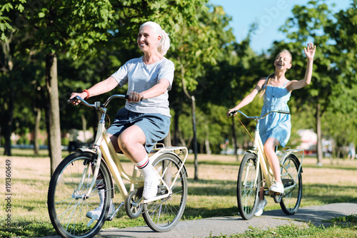 Healthy lifestyle. Delighted positive elderly woman riding a bike and being in a positive mood while leading healthy lifestyle