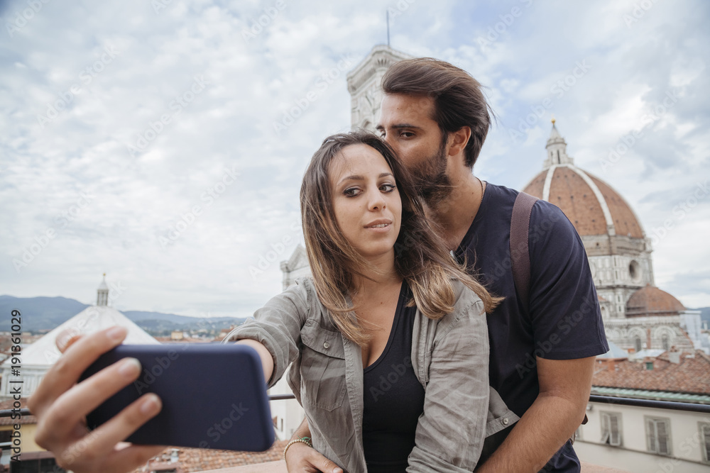 Loving couple taking a selfie in front of the church Santa Maria del Fiore, Florence Cathedral