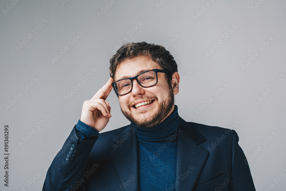 Portrait of handsome young business man smiling and holding glasses with his hand. Isolated in grey background. Close up Portrait of handsome young business man smiling and holding glasses with his hand. Isolated in grey background. Close up