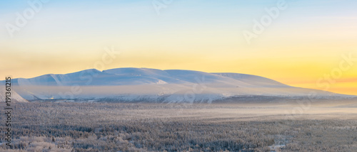 Winter orange sunrise over the Khibiny mountains. Panoramic shot. Fog is spreading over the ground. Apatity  Kola Peninsula  Murmansk region  Russia.