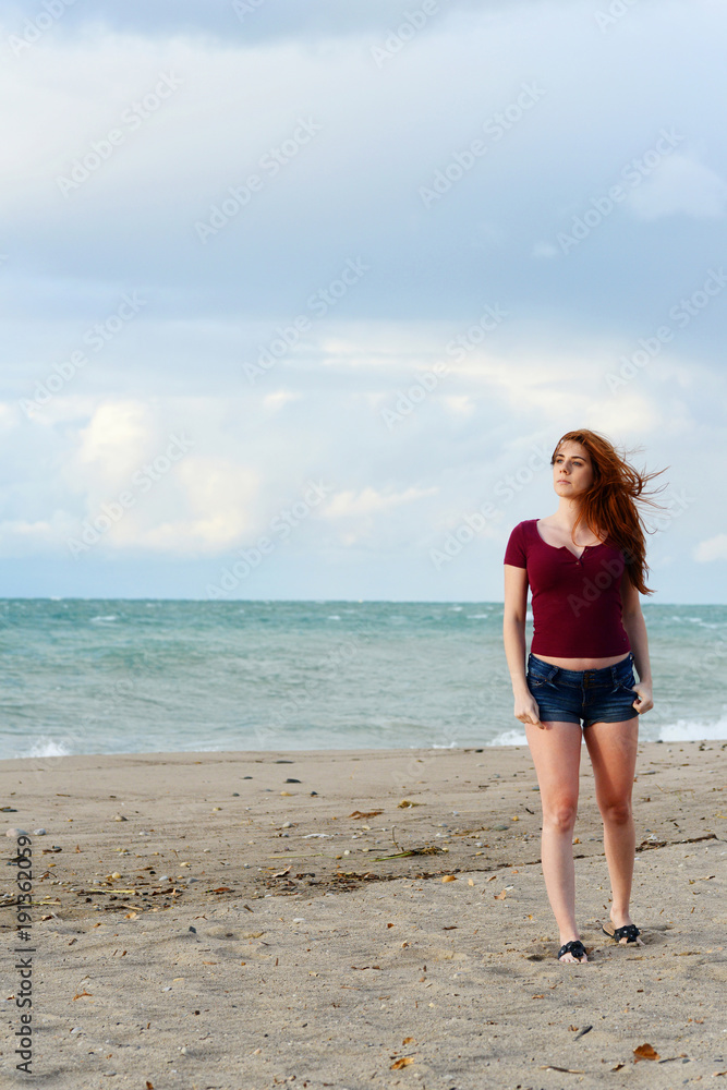 redhead woman on beach with hair blowing in wind