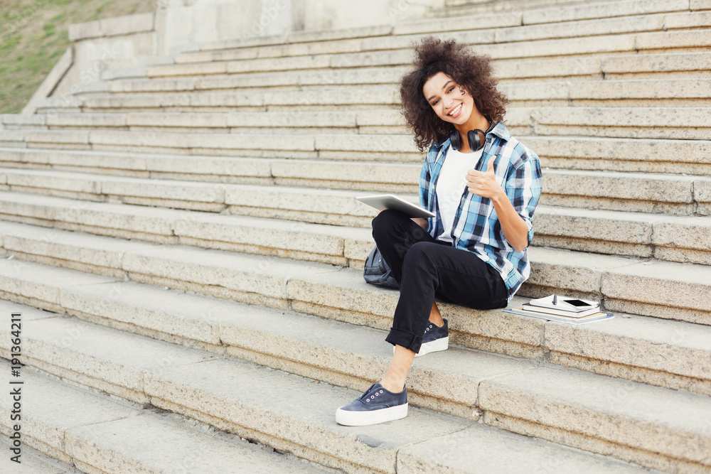 Smiling student sitting on stairs using tablet Smiling student sitting on stairs using tablet