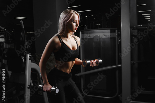 athletic young woman doing a fitness workout with dumbbells