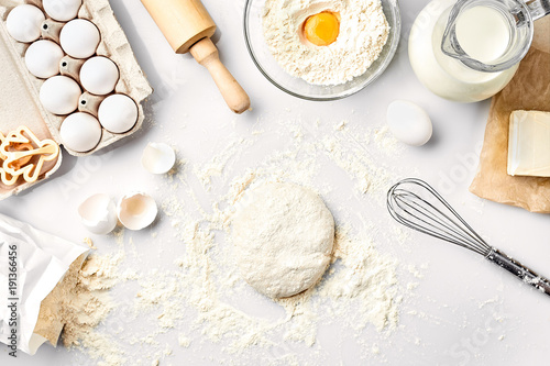 Rauw deeg klaar om te kneden op witte tafel. Bakkerijingrediënten, eieren, meel, boter. Vormen voor het maken van koekjes.
