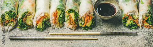 Helathy Asian cuisine. Vegan spring rice paper rolls with vegetables, soy sauce, chopsticks over concrete background. Clean eating, dieting, vegetarian food