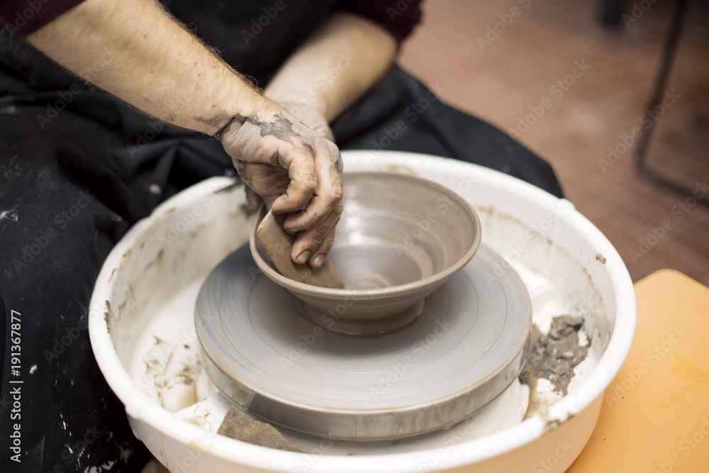 Fototapeta premium Artist makes clay pottery on a spin wheel