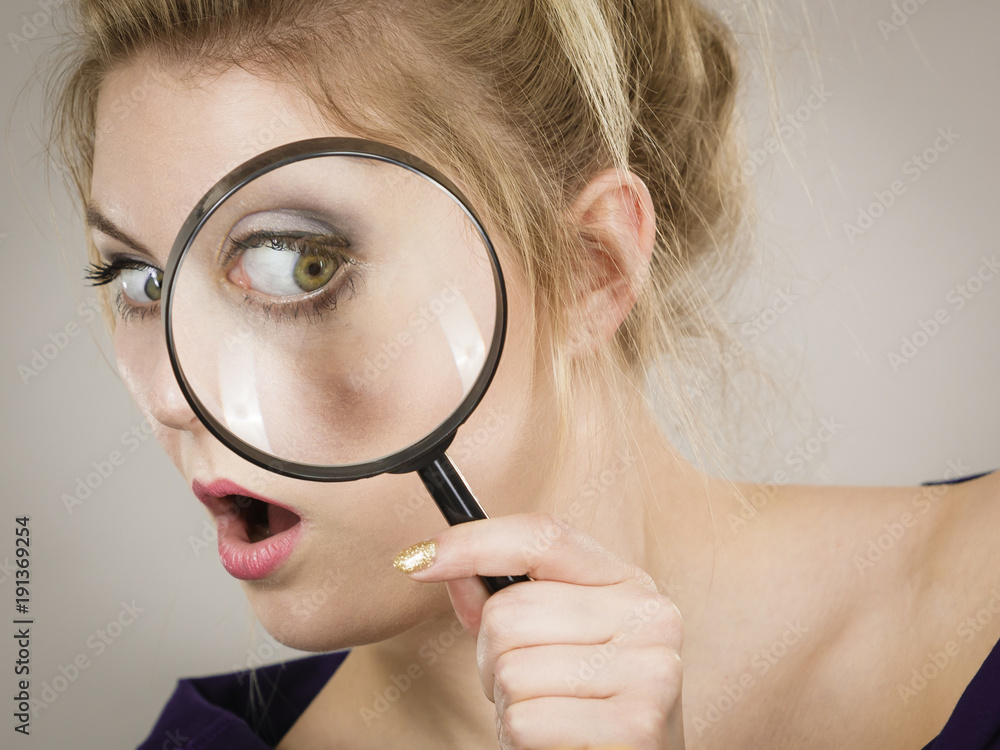Woman holding magnifying glass investigating Woman holding magnifying glass investigating