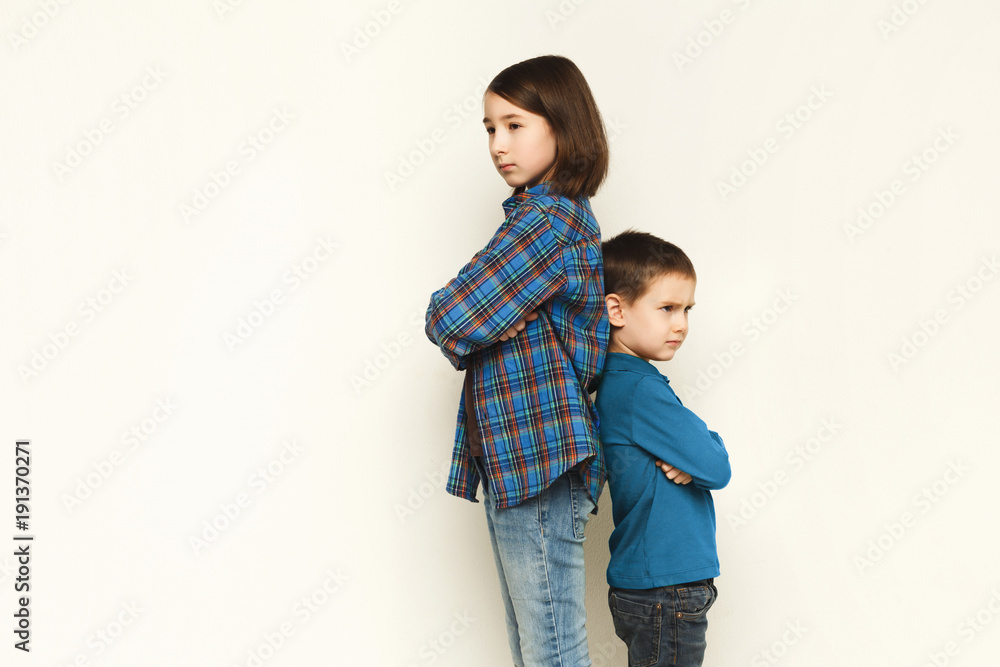 Small girl and her brother standing back to back Small girl and her brother standing back to back