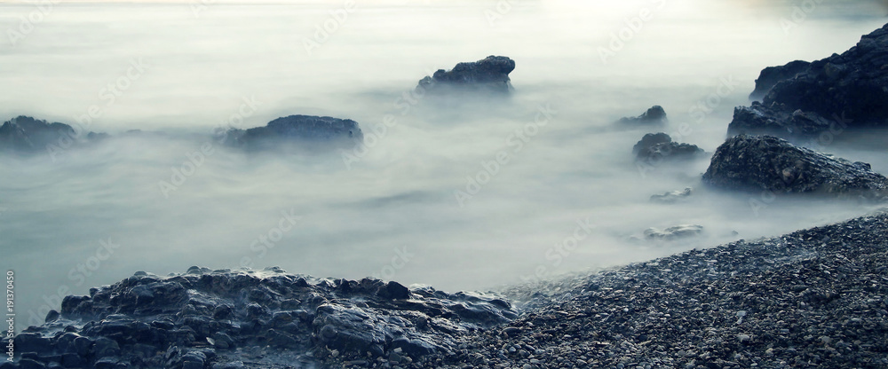Panoramic seascape. Water rolling over rocks at coastline mist long exposure scenic background