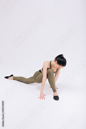 Gymnast girl performs stretching exercises on the white background