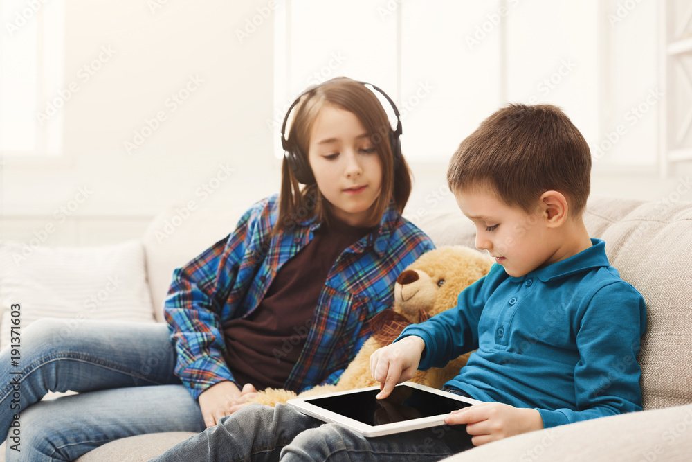 Two kids with gadgets on couch at home Two kids with gadgets on couch at home