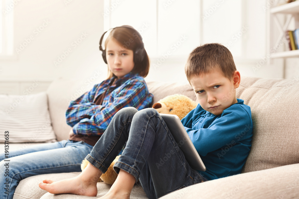 Two kids with gadgets on couch at home Two kids with gadgets on couch at home