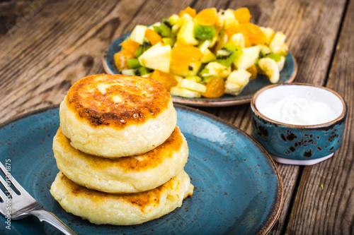 Hot delicious curd pancakes with fruit salad and yogurt