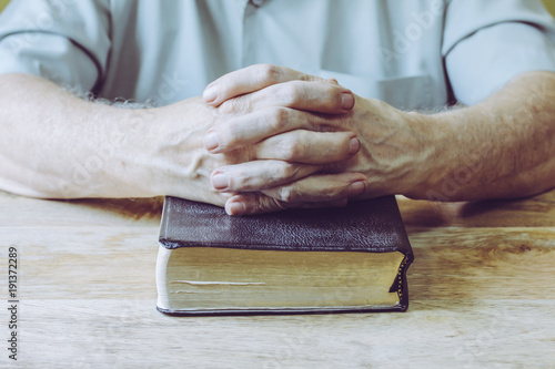 Canvas Print a man hands praying on the holy bible on wooden table