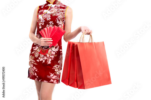 Lower body of Asian beauty woman wearing cheongsam and carry red packet of money and shopping bag in Chinese new year festival event on isolated white background. Holiday and Lifestyle concept. Qipao