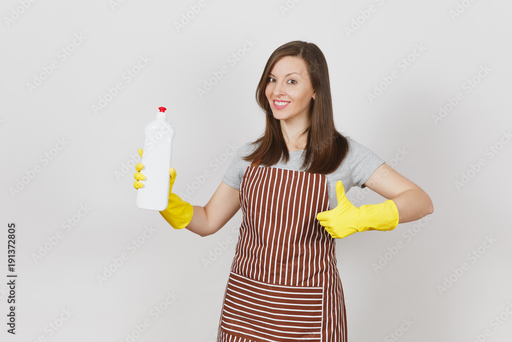 Young smiling housewife in yellow gloves, striped apron isolated on white background. Woman showing thumb up, holding bottle with cleaner liquid for washing and cleaning. Copy space for advertisement. Young smiling housewife in yellow gloves, striped apron isolated on white background. Woman showing thumb up, holding bottle with cleaner liquid for washing and cleaning. Copy space for advertisement.