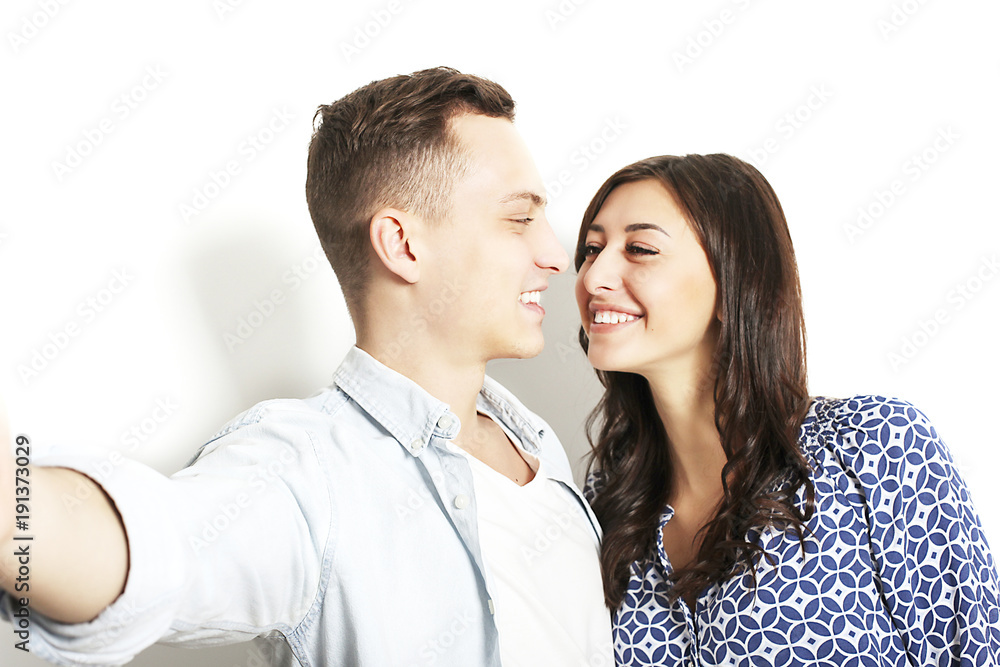 Portrait of two millennial young people, fooling around in front of mobile smartphone camera. Brown eyed model brunette wavy hair girl and male smile in white blank shirt. Portrait of two millennial young people, fooling around in front of mobile smartphone camera. Brown eyed model brunette wavy hair girl and male smile in white blank shirt.