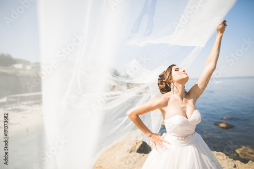 Fotografija Beautiful young bride with bridal bouquet posing on the background sea