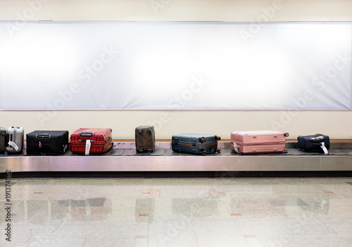 Many luggages are laying down on the conveyor belt at the airport.