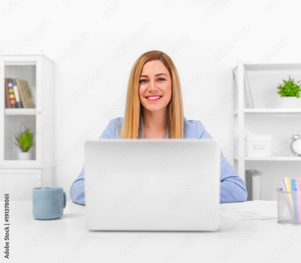 Attractive blonde in a blue business suit in a bright office working on a laptop. Attractive blonde in a blue business suit in a bright office working on a laptop.