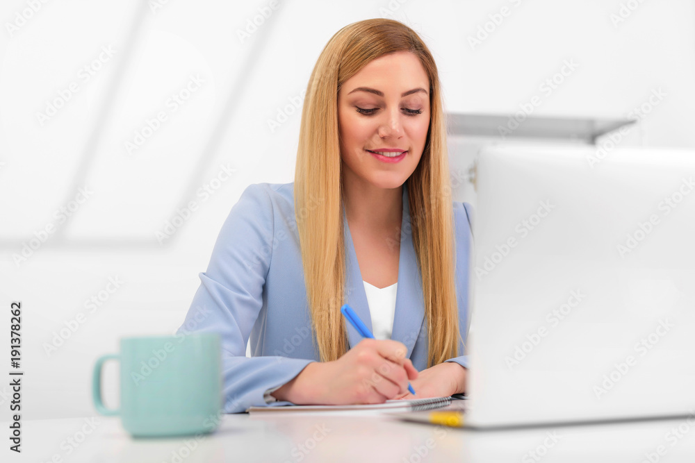 Attractive young woman working with documents and laptop in the workplace in a white office. Attractive young woman working with documents and laptop in the workplace in a white office.