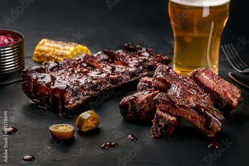 Tablou pe pânză Pork ribs in barbecue sauce and a glass of beer on a black slate dish