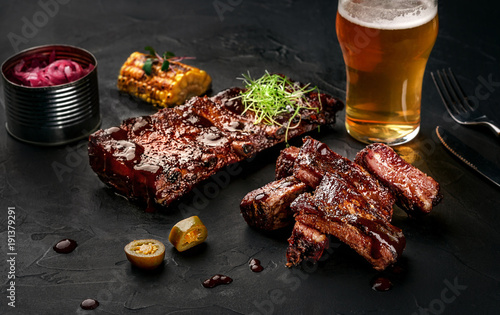 Fotografie Pork ribs in barbecue sauce and a glass of beer on a black slate dish