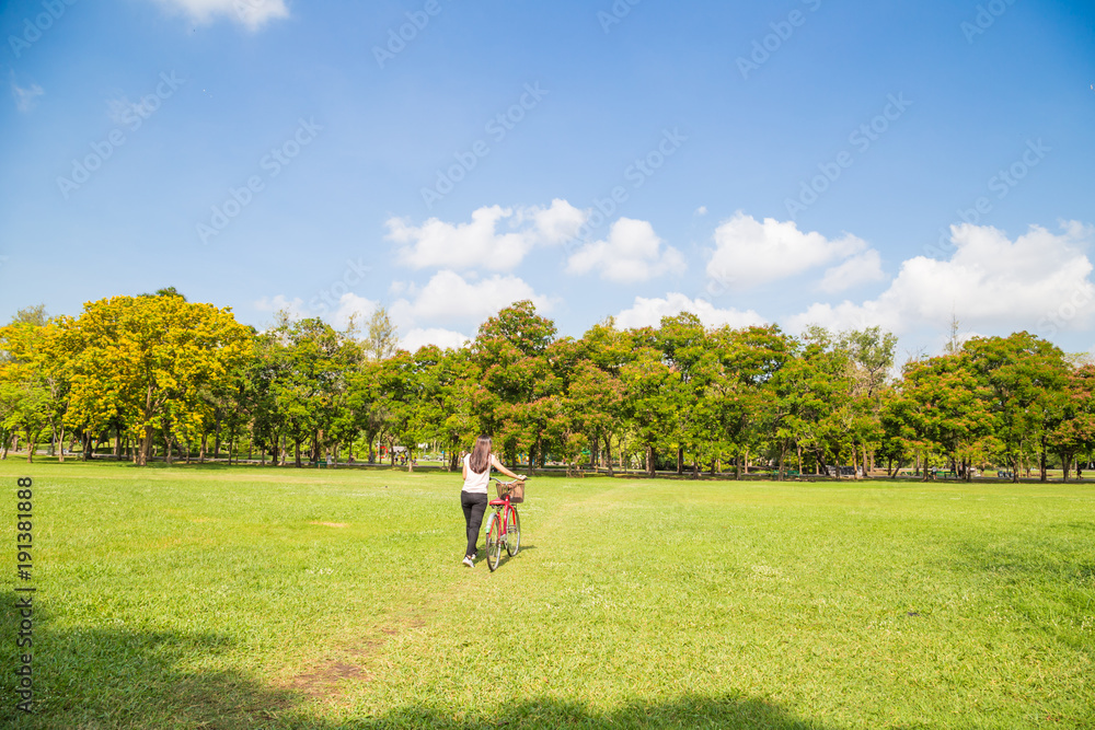 Young asian women with bicycle on green meadow Young asian women with bicycle on green meadow