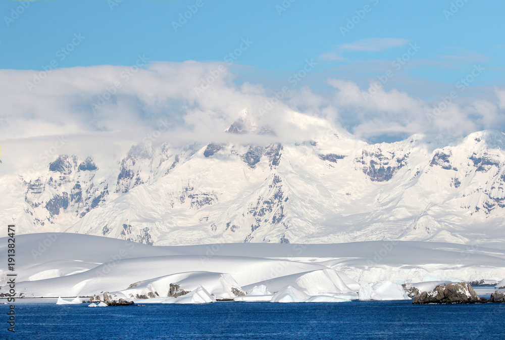Antarctic ocean, Antarctica. Glacier Snow Covered Mountain. Dramatic blue Sky background