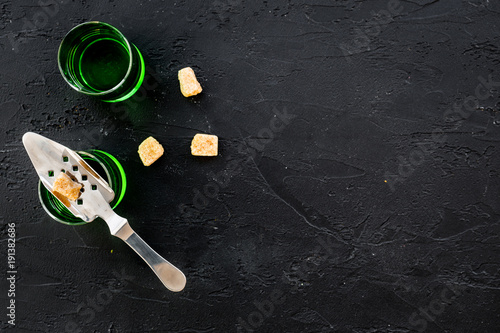 Traditions of drinking absinthe. Special spoon and sugar cubes near shots on black background top view copy space