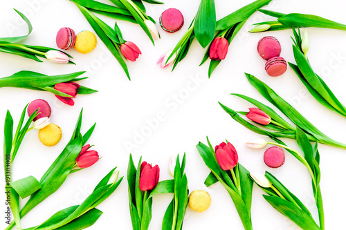 Spring gift. Flowers and sweets. Tulips and sweets macarons on white background top view copy space