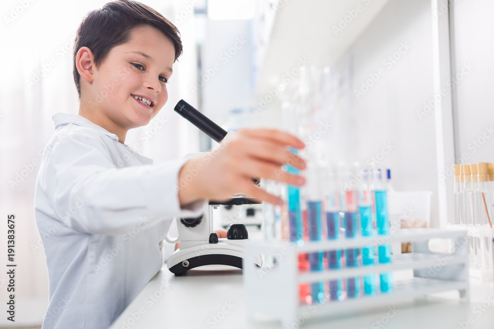 Vigorous enthusiastic boy reaching vial Vigorous enthusiastic boy reaching vial