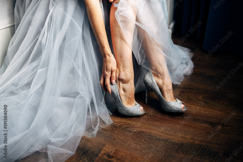 Bride puts on her silver wedding shoes, grey wedding dress on background  Stock Photo | Adobe Stock
