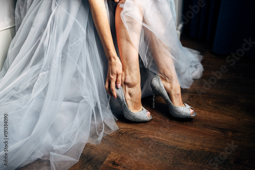 Bride puts on her silver wedding shoes grey wedding dress on background Stock Photo Adobe Stock