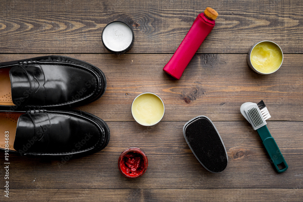 Shoe care products. Leather men shoes, shoe polish, brushes, wax on dark wooden background top view Shoe care products. Leather men shoes, shoe polish, brushes, wax on dark wooden background top view