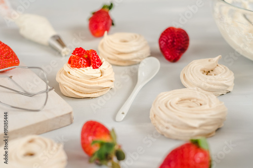 Strawberry pavlova cake nests, meringue decoration on a culinary table