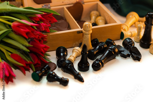 Bouquet of red tulips, chocolate hearts and chess photo