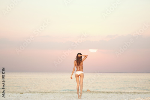 beautiful sexual young woman stands on the beach against the sea and sky. happy woman enjoying summer vacation